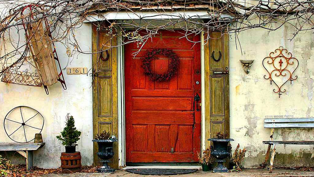 Red wooden front door with yellow wooden sidelights. A front door in need of painting and repair sets a bad tone for guests visiting your home. 