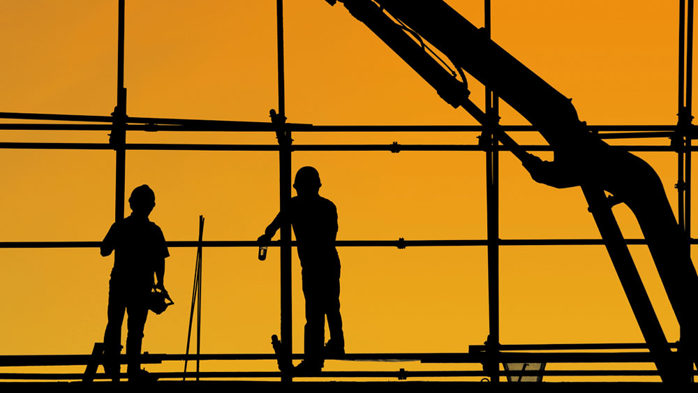 Silhouette of two construction workers on scaffolding, signifying the current condition of the architectural and construction industries.