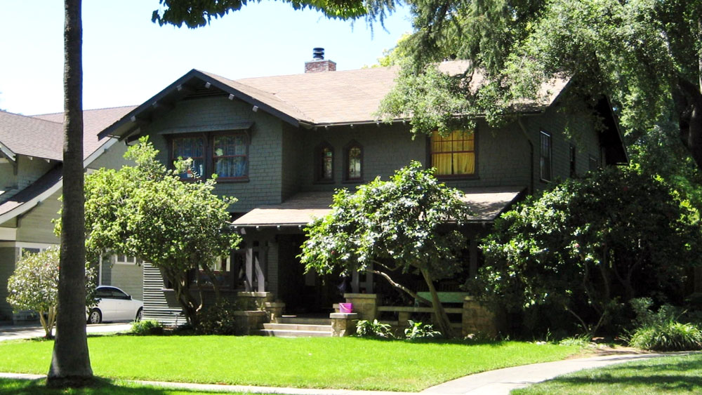 Exterior of the 2-story craftsman with gray-green painted wood shingle siding and a stone porch, movie scene home of Lorraine Baines McFly