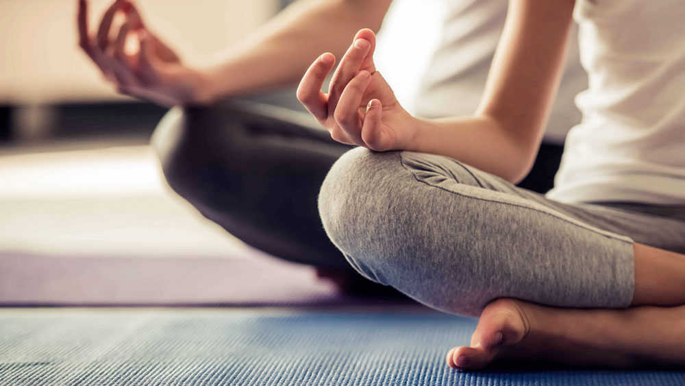 Two people sitting cross legged in gyan mudra position signifying the power of proper architectural design of a meditation room in your new home.