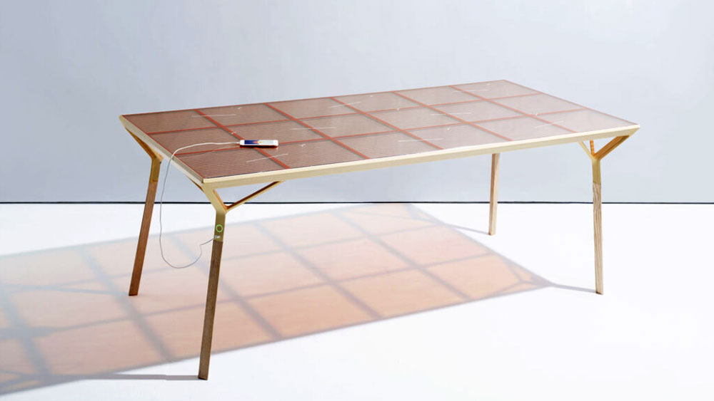 A modern gold frame table dining table with a rose gold glass top, integrated with dye-sensitized solar cells that create electrical current.