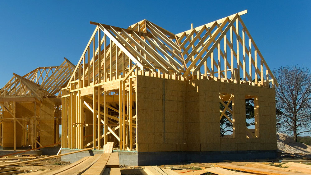 A wood frame of a home under construction that is being covered with OSB as exterior sheathing, which can pose a health risk due to off-gassing.