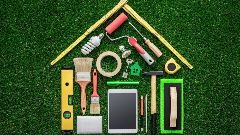 Calculate Your Exposure Construction tools laid out in the shape of a house on green grass background, signifying being involved in your home design to calculate VOC exposure