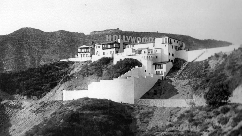 Castillo de Lago home circa 1926 designed by John Delario with a backdrop of the Hollywoodland sign in Los Angeles, California