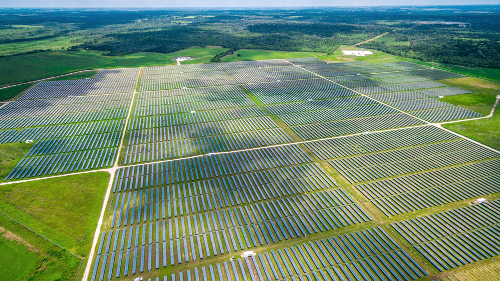 Acres of solar panels comprising a large solar farm in the middle of green pastures