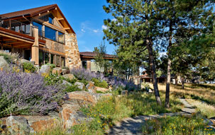 Denver Xeriscape Stone house in Denver surrounded by native trees, large boulders, and xeriscape with a gray gravel pathway