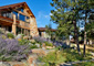 Stone house in Denver surrounded by native trees, large boulders, and xeriscape with a gray gravel pathway