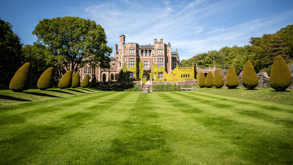 A 19th century Tudor style castle in Sweden with a manicured green grass front lawn, signifying the aristocrats that began the trend of planting lawns