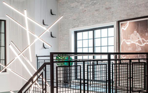 Rehabbed Firehouse Foyer The foyer of a rehabilitated firehouse features a modern and sleek Monorail Cirrus Float R1 Rectangular Suspension chandelier from PureEdge Lighting.