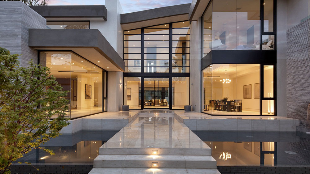 Organic modern residence with opposing glass curtain walls, a water feature, and two story entryway