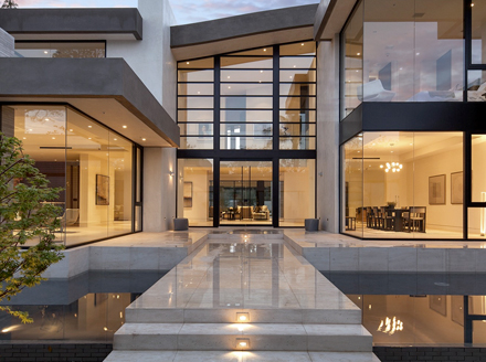 Organic modern residence with opposing glass curtain walls, a water feature, and two story entryway