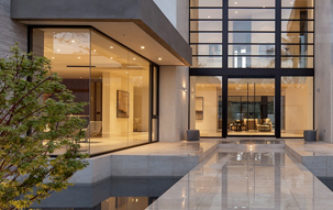 Organic modern residence with opposing glass curtain walls, a water feature, and two story entryway