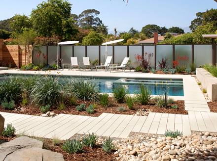 Xeriscaping Isn't Just For The Desert A modern, rectangular pool surrounded by a xeriscaped yard with ornamental grasses, river rocks, and wood mulch.